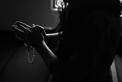 祈祷时拿着念珠的女人的剪影
